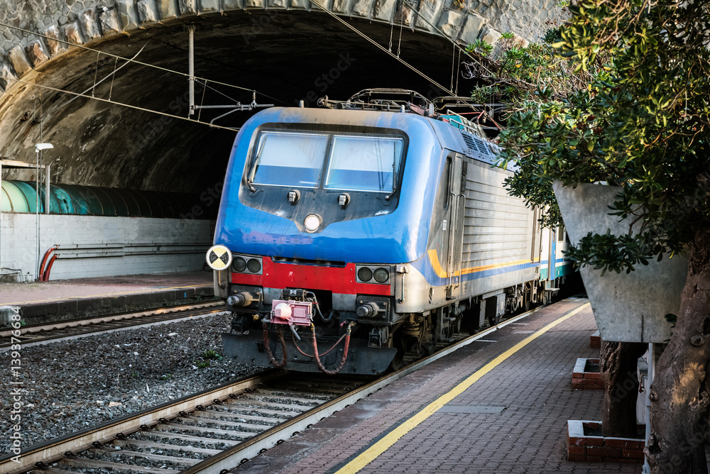 Passenger train driving out from tunnel near Riomaggiore town, Cinque Terre, Italy