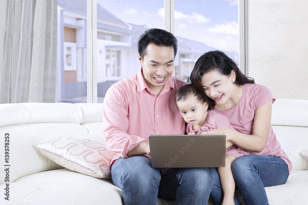 Parents using a laptop with their daughter Parents using a laptop with their daughter