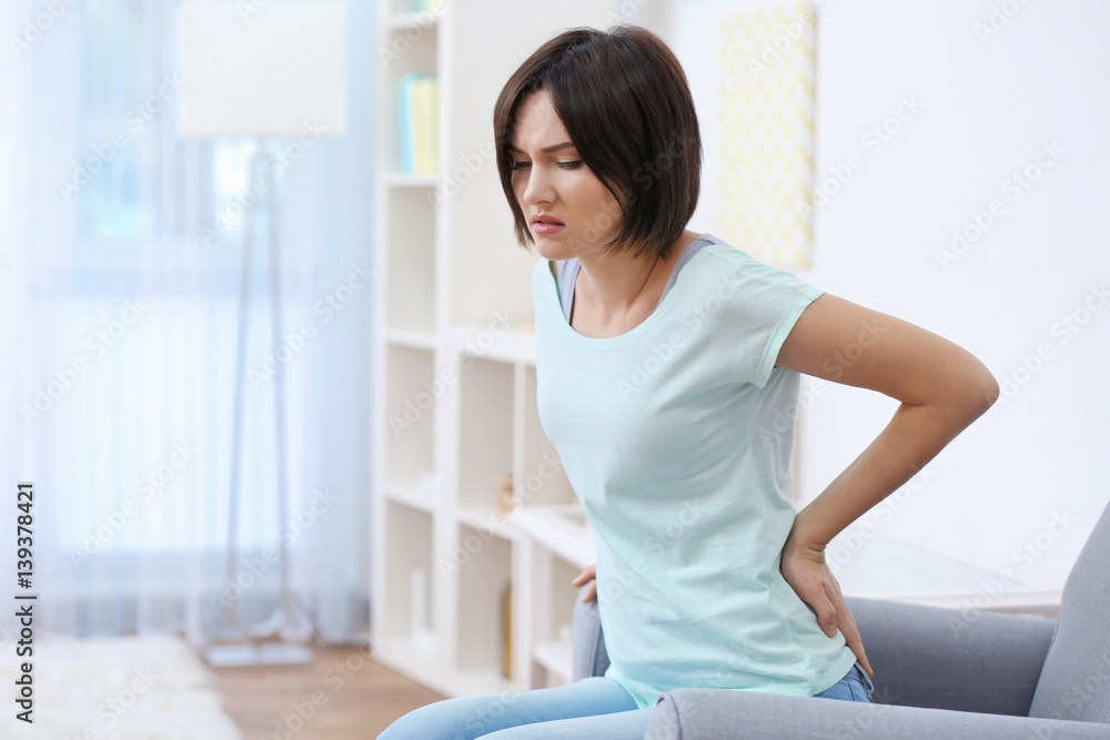 Beautiful young woman suffering from backache at home Beautiful young woman suffering from backache at home