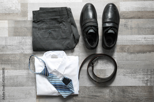 Clothes of schoolboy on wooden floor, flat lay