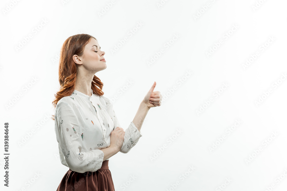 cute woman in a light shirt showing thumbs up, side view cute woman in a light shirt showing thumbs up, side view