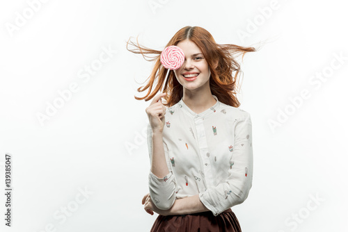 happy woman holding a round lollipop in front of face