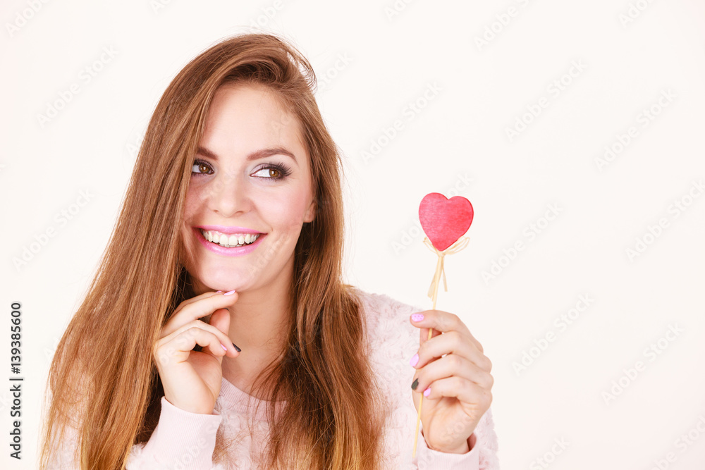 Flirty woman holding red wooden heart on stick Flirty woman holding red wooden heart on stick