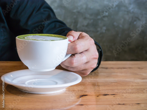 Asian man holding a cup of hot matcha latte. Asian man holding a cup of hot green tea latte.