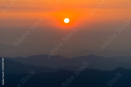 The sun over the layers of the mountain in sunset. © Tawatchai