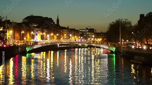 Night View of the Ha'penny Bridge Over Liffey River in Dublin, Ireland. Night Cityscape With Colourful Light Reflection on the Water Surface. Hapenny Bridge, Nigthtime. photo