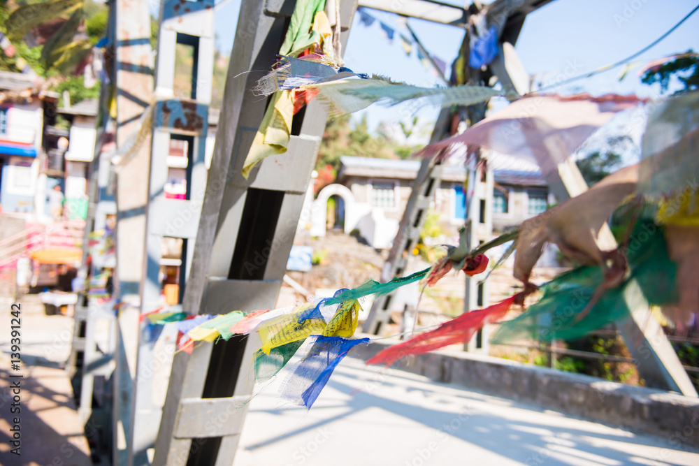 colorful prayer flags hang on river bridge in Nepal