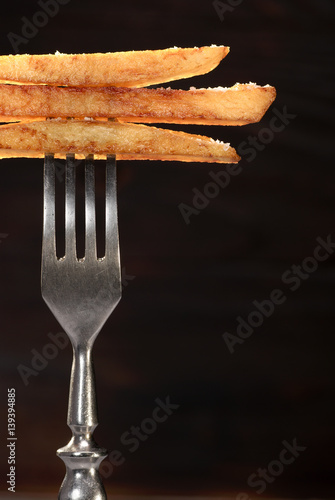 French fries and fork on a dark wooden background.