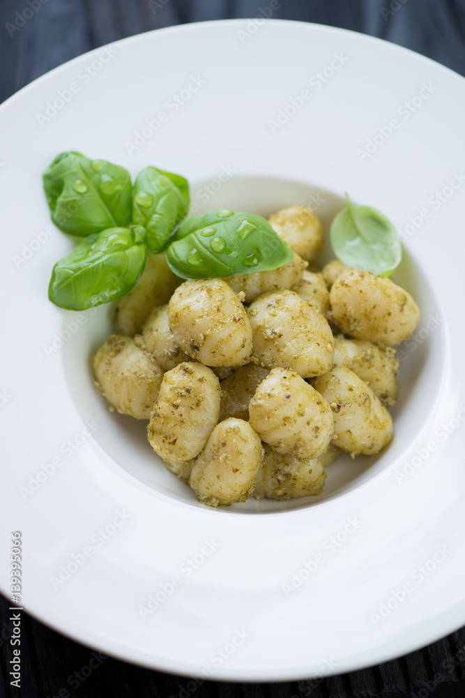 Close-up of potato gnocchi served with basil pesto sauce and fresh basil leaves, selective focus Close-up of potato gnocchi served with basil pesto sauce and fresh basil leaves, selective focus