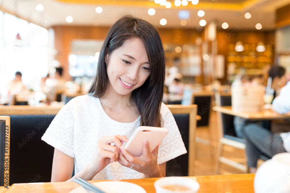 Woman using mobile phone at chinese restaurant Woman using mobile phone at chinese restaurant