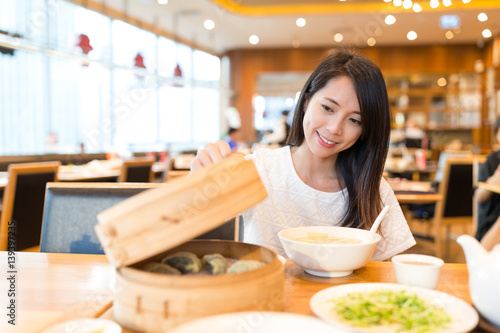 Woman open the bamboo steamer in chinese restaurant