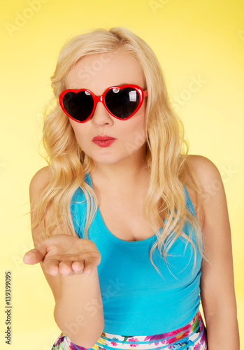 Beautiful woman in sunglasses sending a kiss