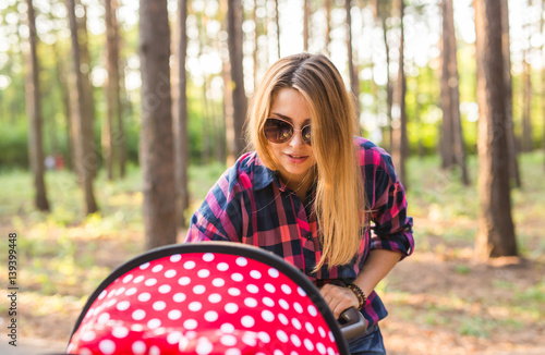 Closeup of mother with baby in pram walking in summer park