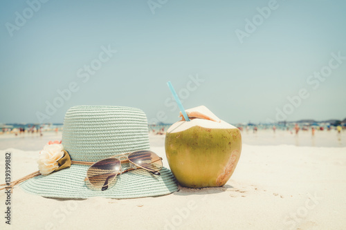 Summer vacation concept with straw hat, sunglasses and coconut cocktail on sandy tropical beach