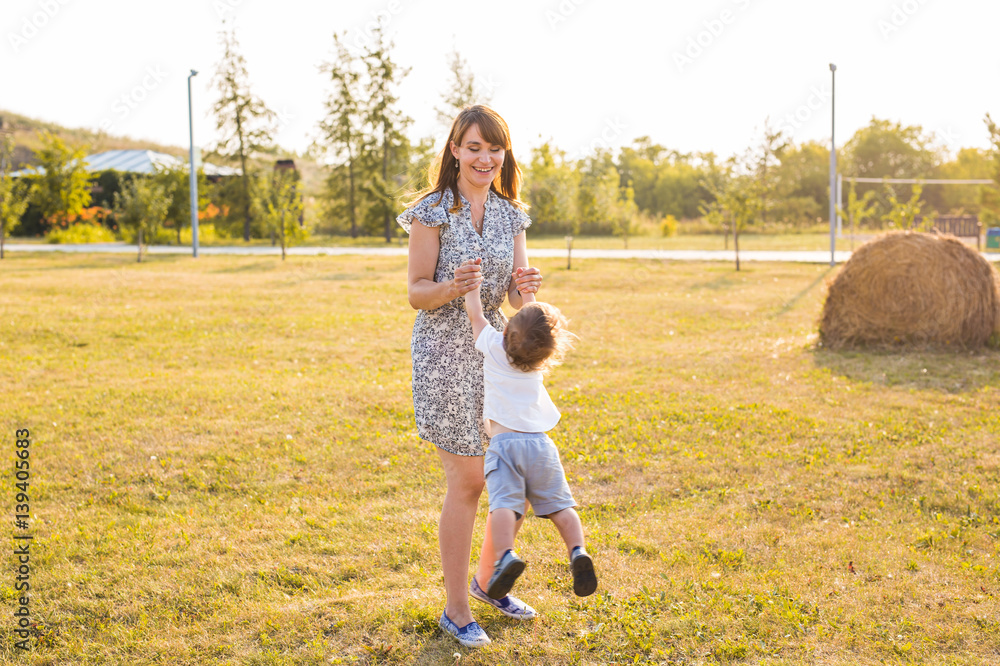 Fototapeta premium Cute cheerful child with mother play outdoors in park
