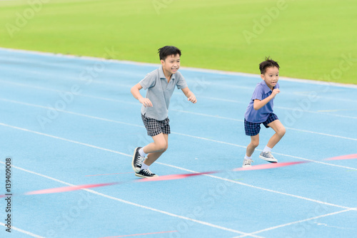 Young Asian boy running on blue track in the stadium