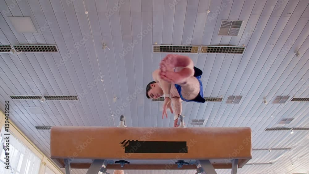 Young gymnast doing routine exercises on pommel horse HD slowmotion video. Olympics athlete