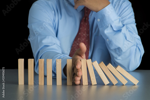 Close up view on hand of business woman stopping falling blocks on table for concept about taking responsibility.
