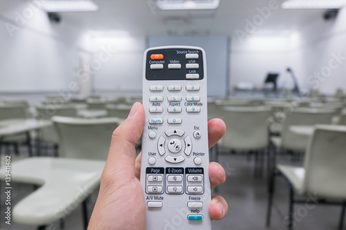 Holding remote control  projector in hand in classroom