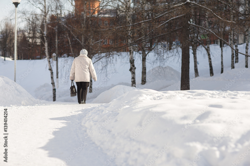 Older woman walking on a snowy road