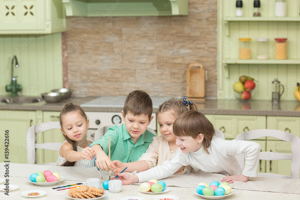 Obraz premium Easter day. A group of children paint Easter eggs and laugh.