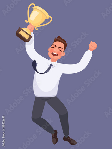 Winning at work. Businessman with strong emotions on his face is jumping holding the cup winner