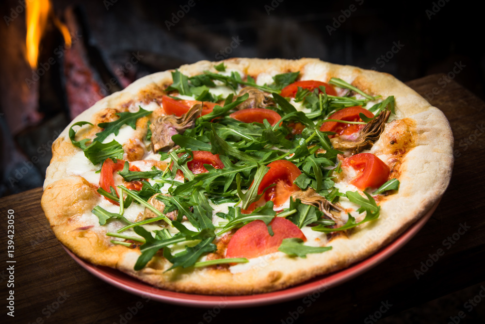 Pizza vegetariana con carciofi, rucola, pomodoro e mozzarella