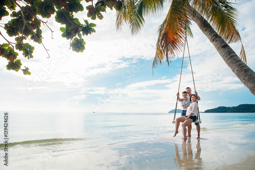 Family sit on Swing tropical beach © Olga
