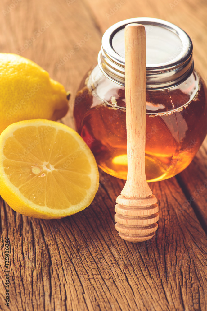Jars of honey with lemons on wooden table Jars of honey with lemons on wooden table