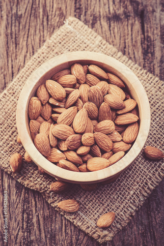almonds in a bowl on grained wood background