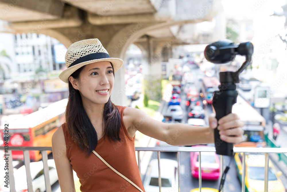 Woman holding video stabilizer to take video at street of Bangkok