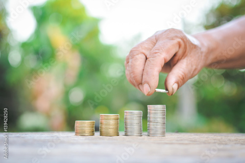 Hand holding coin on old wood tree bokeh background.concept save money