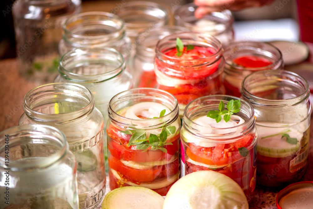 Canning fresh tomatoes with onions for winter in jelly marinade. A shot of basil leaves on top of a red ripe tomato slices and onion rings being put in jar.
Canning fresh tomatoes with onions for winter in jelly marinade. A shot of basil leaves on top of a red ripe tomato slices and onion rings being put in jar.