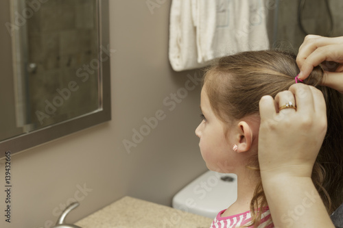 mother putting daughters hair in pigtails