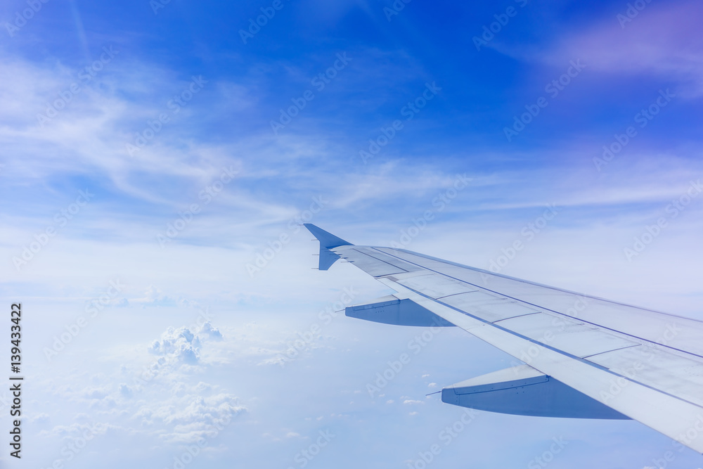 Fototapeta premium Looking thru airplane 's window seeing wing of airplane ,white clouds and blue sky
