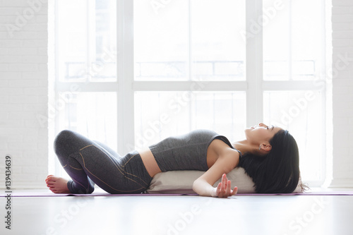 Beautiful young yoga girl lying in asana Shavasana