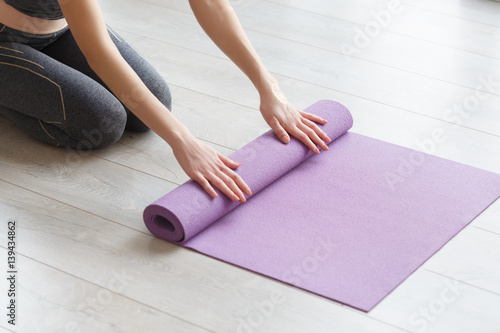 Young yoga Woman rolling her lilac mat
