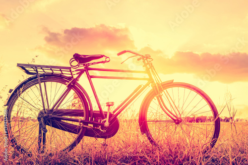 Landscape picture Vintage Bicycle with Summer grass field at sunset ; vintage filter style.classic bicycle,old bicycle style for greeting Cards ,post card