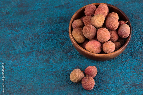 Lychee in a wooden bowl on a blue cement background photo