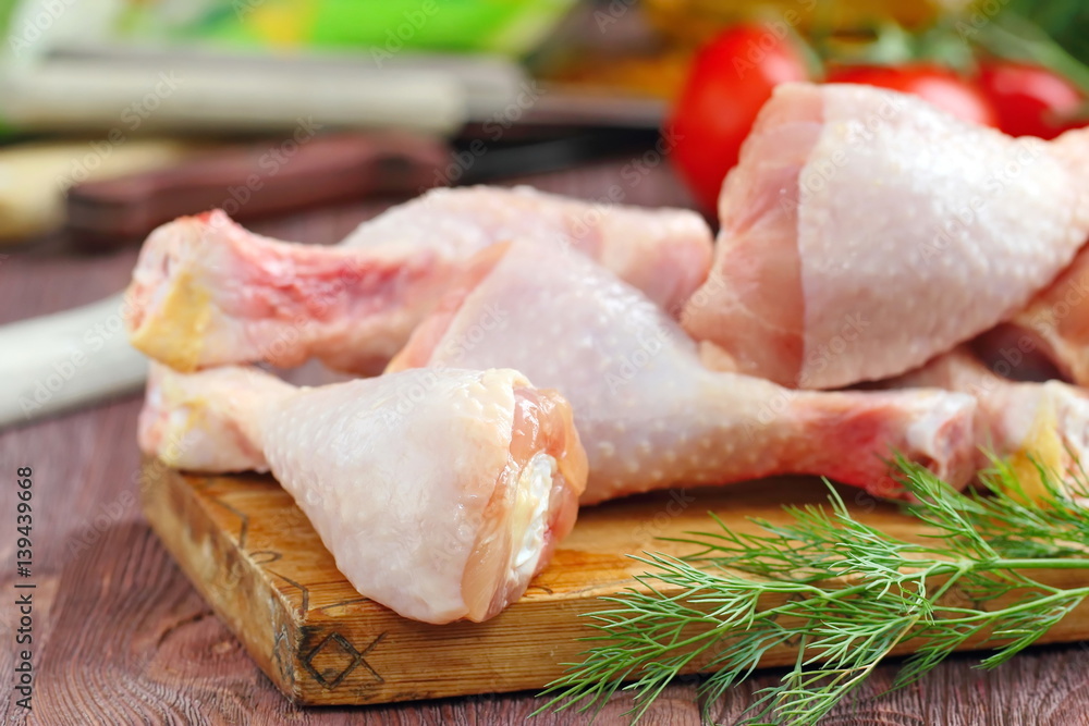 Raw chicken legs with spices and vegetables on a cutting board Raw chicken legs with spices and vegetables on a cutting board