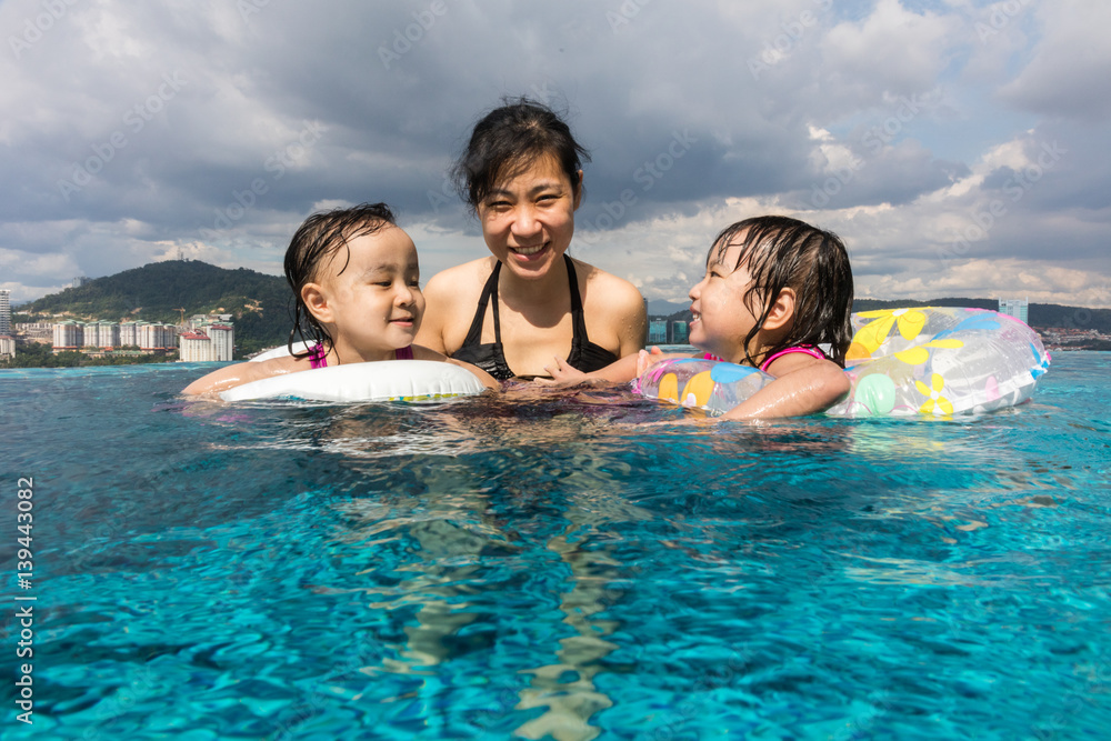 Asian Chinese family playing at the outdoor swimming pool Asian Chinese family playing at the outdoor swimming pool