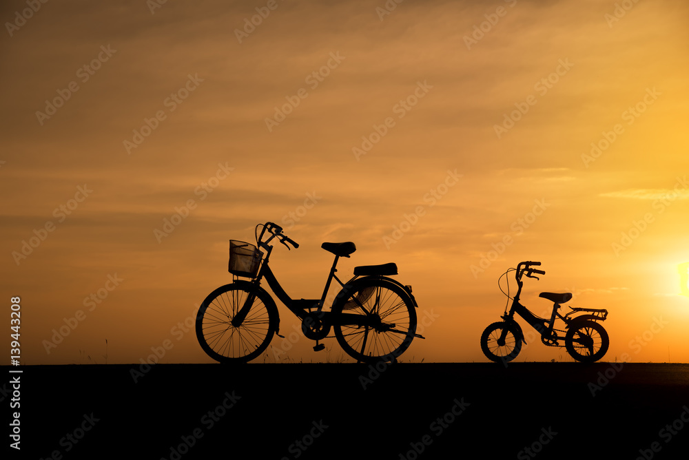 Fototapeta premium Silhouette of vintage bicycles on the road with the sunset background.
