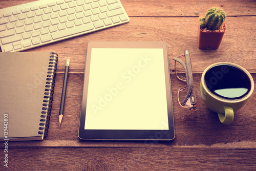 mockup tablet similar to ipad style on wood desk white display.keyboard and office stuff, workplace