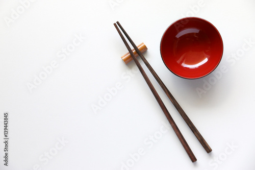 Top view of chopsticks red bowl on white table background.Flat lay