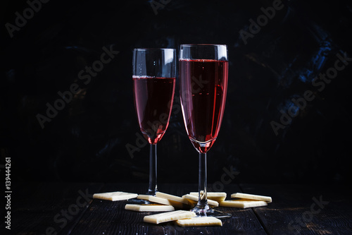 Rose sparkling wine in glasses and white chocolate, dark background, selective focus