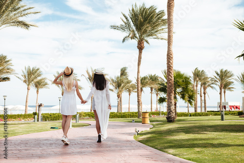 Back view of two young women walking on summer resort