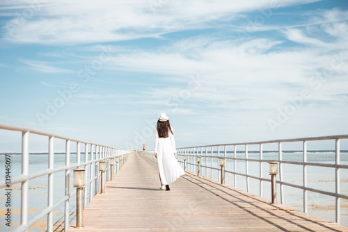 Back view of beautiful young woman walking on pier