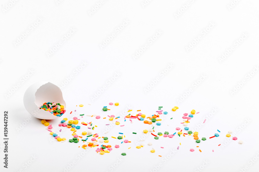 Egg shell colorful sugar sprinkle dots on white table with copy space. Easter concept