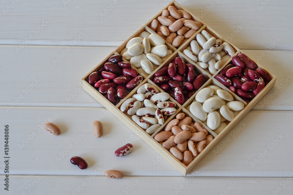 Assortment of beans in wooden box on white wooden background. Kitchen concept Assortment of beans in wooden box on white wooden background. Kitchen concept