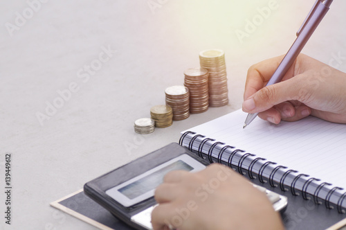 hand of women writing on note book with calculator in morning